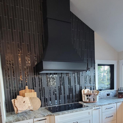 Modern kitchen with dark tiled backsplash, black range hood, and light granite countertop.